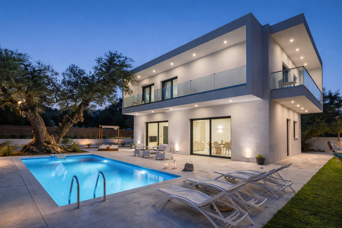 Agua – Bel Air - modern two-storey villa exterior with illuminated pool, sun loungers and olive tree at dusk