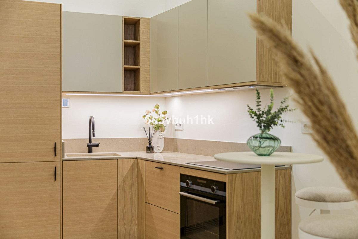 Calle Jinetes – Málaga Centro - modern kitchen with wood cabinetry, sage upper cabinets, integrated oven, and under-cabinet lighting