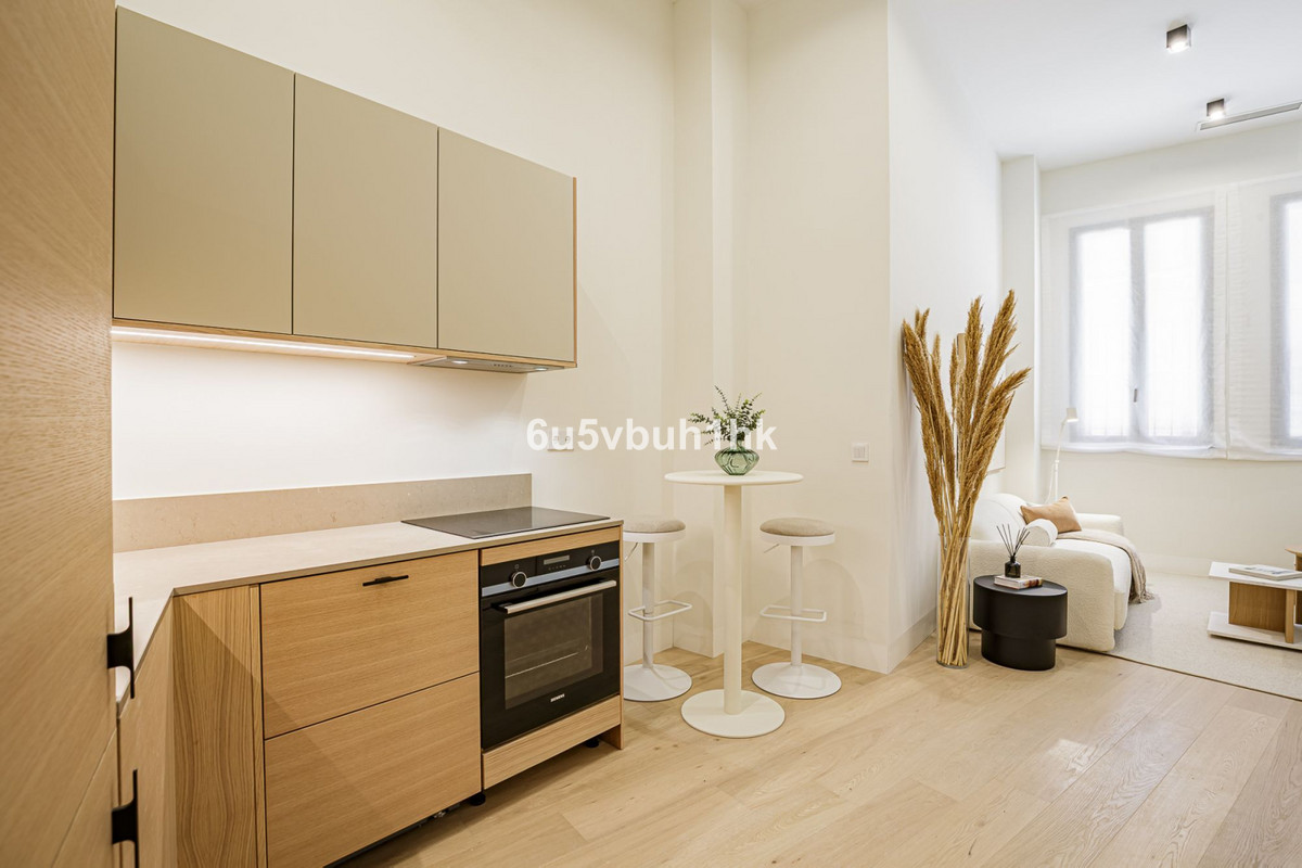 Calle Jinetes – Málaga Centro - open-plan kitchen and living area with light wood cabinetry, induction hob, oven, bar-height dining table and lounge seating