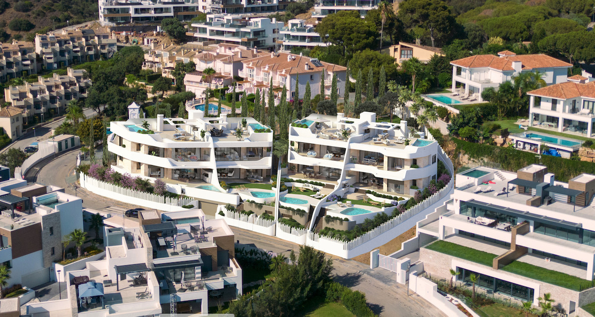 Golden Eight – Marbella - aerial view of luxury white residential complex with rooftop terraces and private pools surrounded by lush greenery