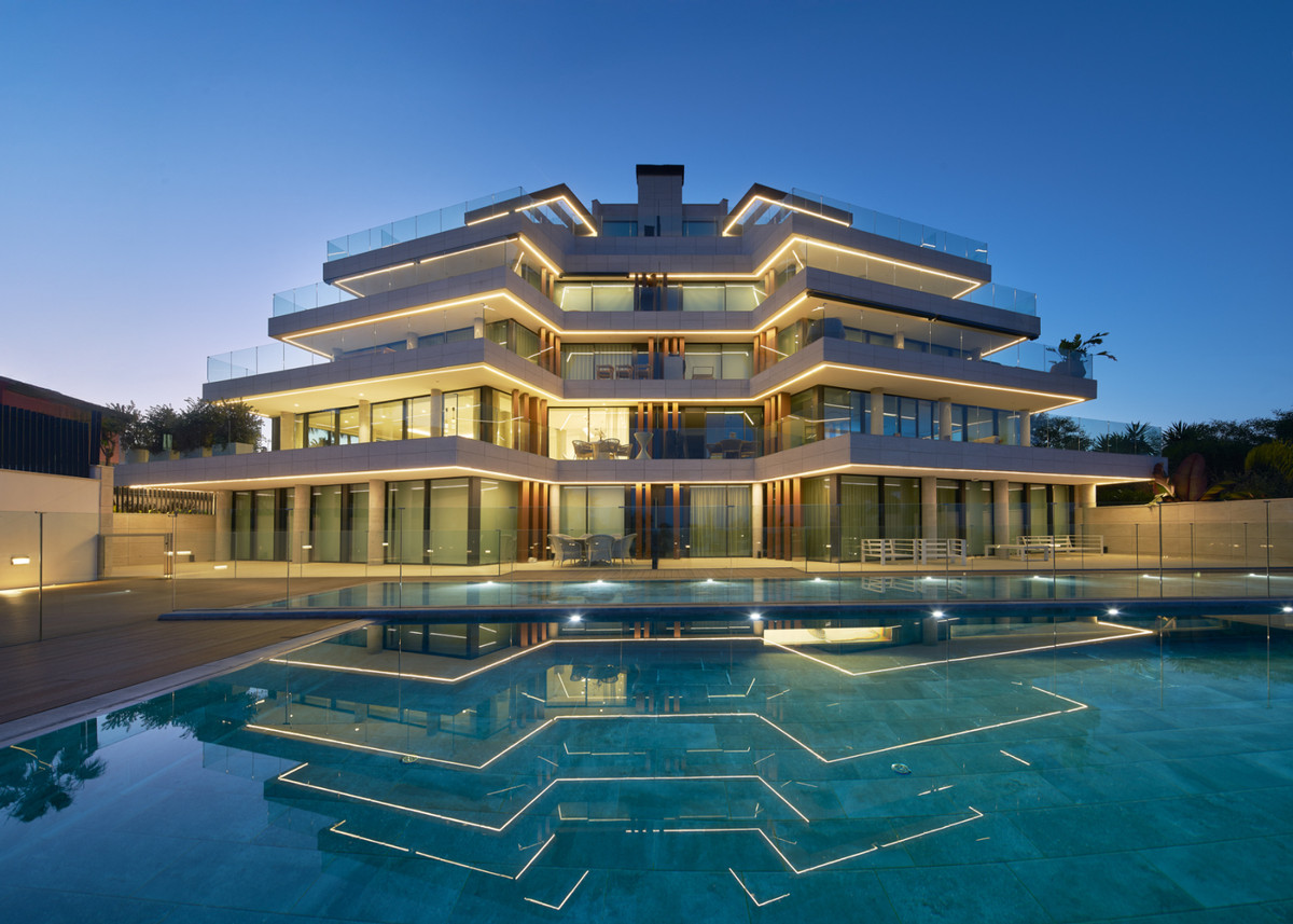 The Sapphire – Estepona - illuminated multi-storey luxury facade reflected in a geometric outdoor pool at dusk