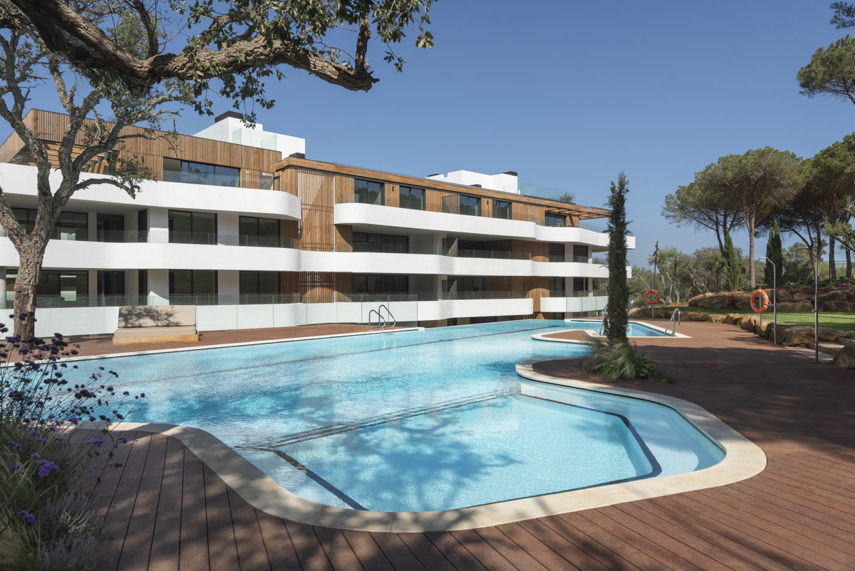 Village Verde – Sotogrande - luxury exterior with curved swimming pool and wooden decking surrounded by mature pine trees