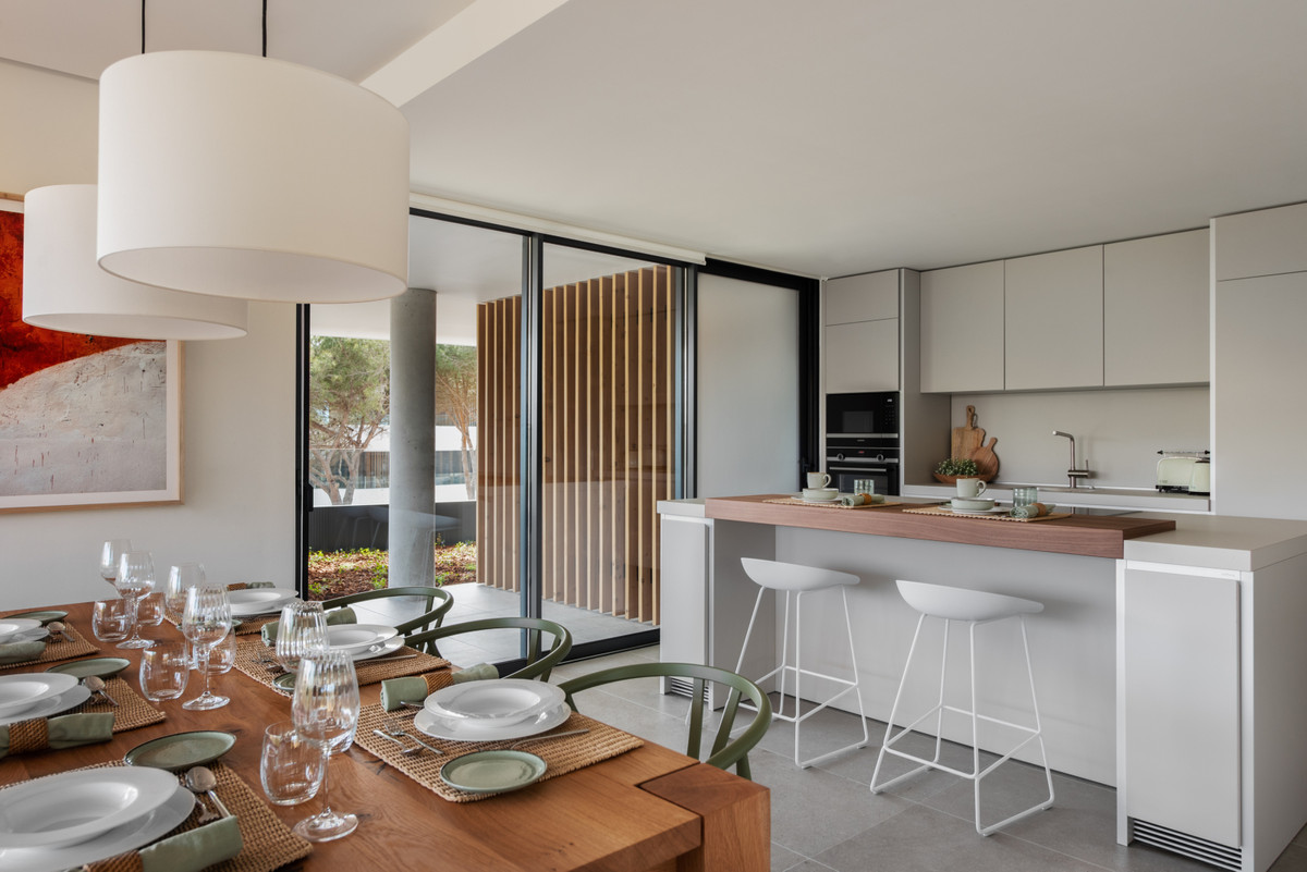 Village Verde – Sotogrande - open-plan kitchen and dining area with island, bar stools, and floor-to-ceiling sliding doors