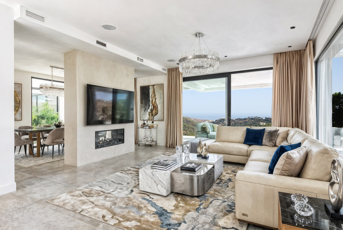 ZOE LUXE – Benahavís - luxury living room with leather sectional sofa, marble coffee table, crystal chandelier and panoramic sea views