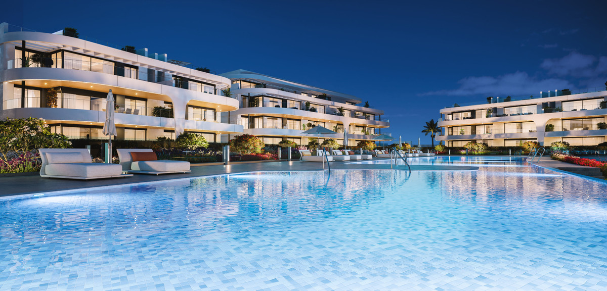 Naya Residences – Atalaya - illuminated outdoor swimming pool and white curved apartment buildings at dusk