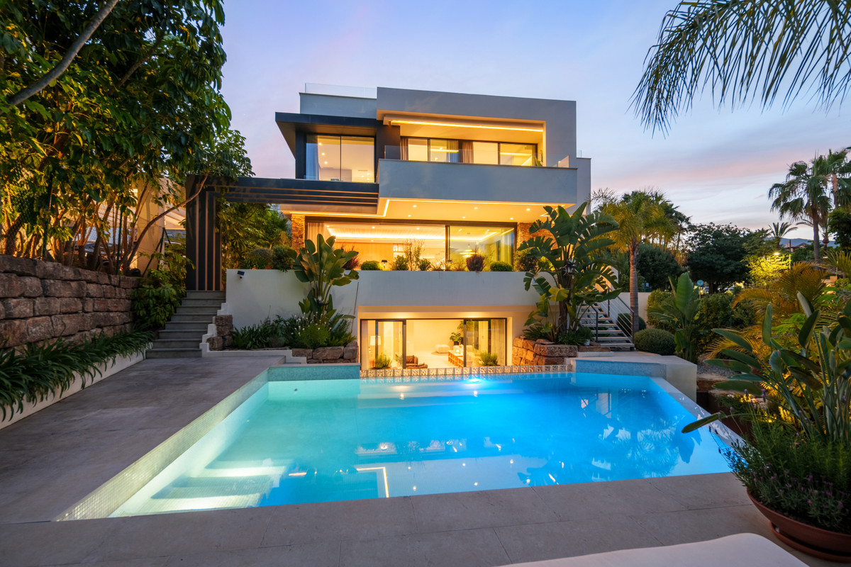 Belfry 1 – Estepona - modern luxury villa exterior with illuminated pool, terraces and tropical gardens at dusk