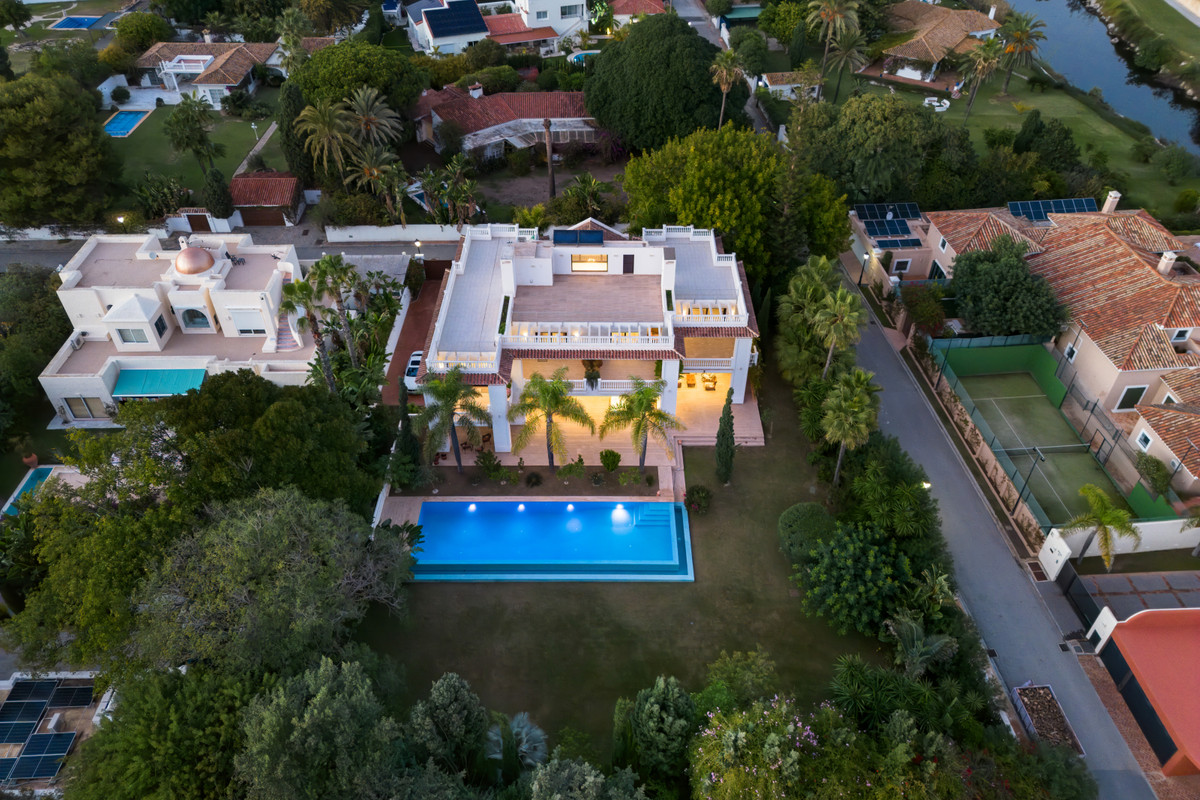 Villa Murcia – Estepona - aerial view of luxury villa with illuminated infinity pool, lush gardens and rooftop terrace at dusk