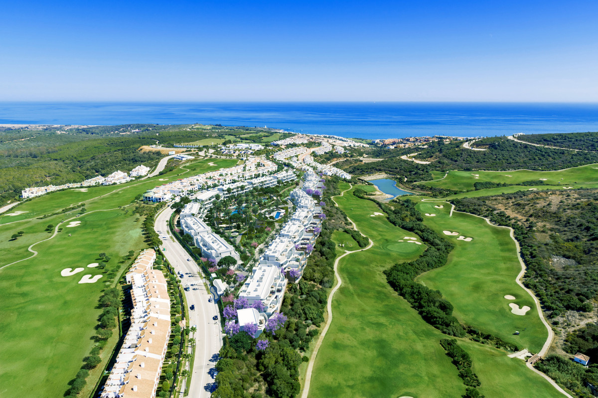 Serenity Frontline Golf Homes and Beach Club – PHASE III – La Alcaidesa - aerial view of luxury white residential development surrounded by lush golf fairways with Mediterranean Sea backdrop