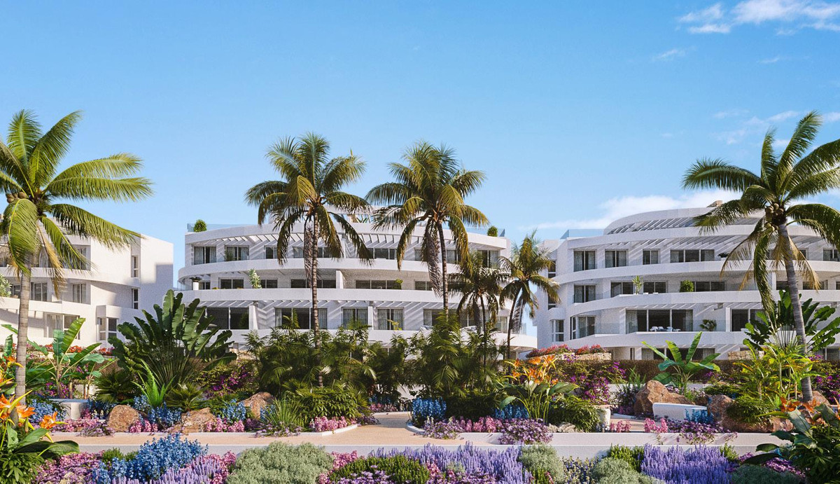 Royal Palms Mijas – FASE IV-2 – La Cala de Mijas - exterior facade of white curved apartment buildings surrounded by tropical palm trees and vibrant flower gardens
