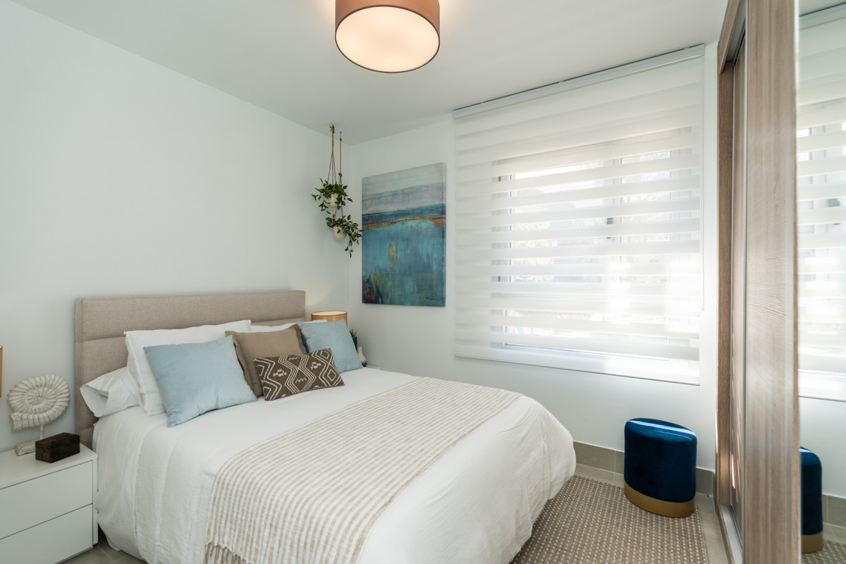 Solana Village – Fase 3 – La Cala Golf - elegantly styled bedroom with white bedding, soft blue accents, zebra blinds and hanging plants
