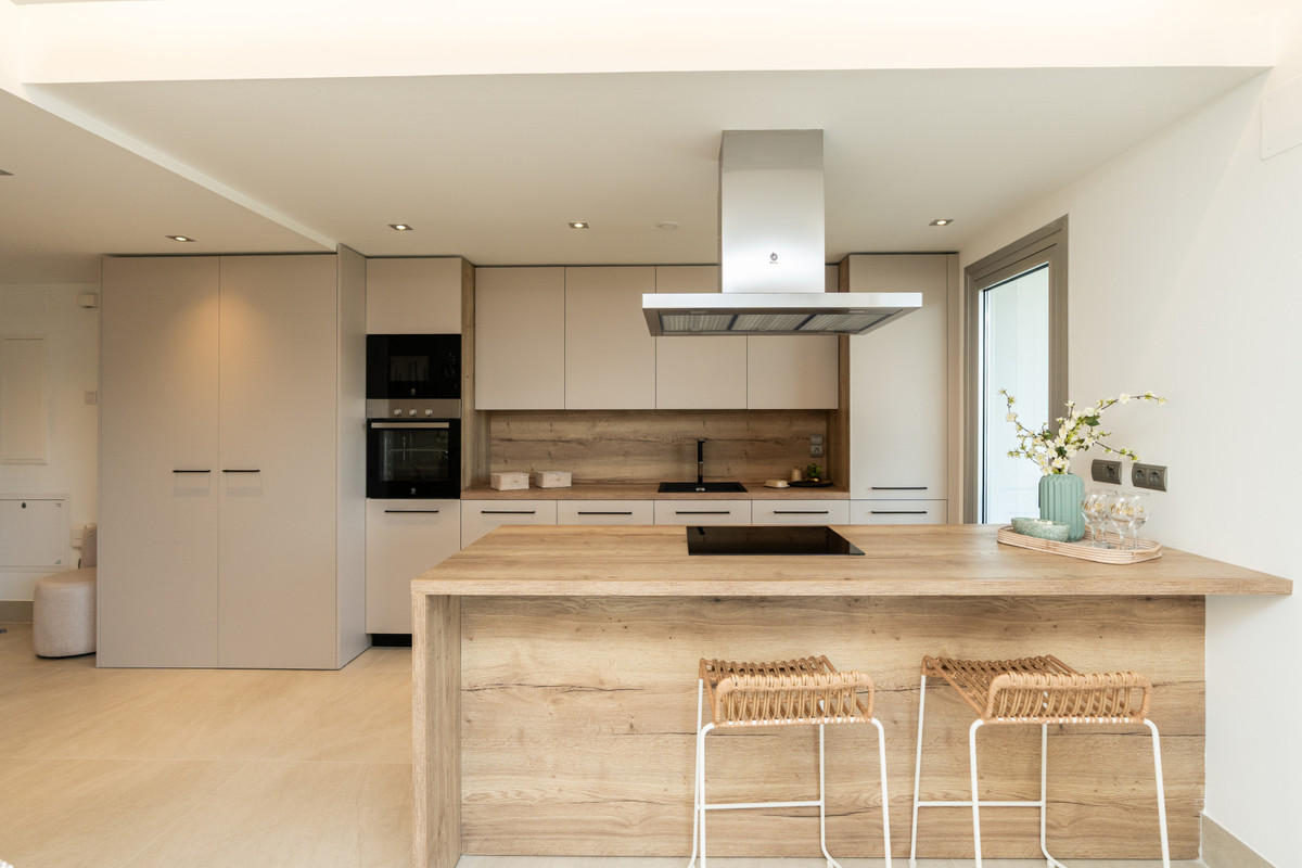 Solana Village – Fase 3 – La Cala Golf - modern open-plan kitchen with wood island, bar stools and integrated appliances